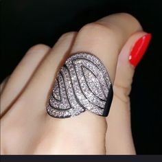 a woman's hand with a ring on it and red nails in the background