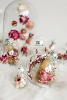 three glass ornaments with flowers in them