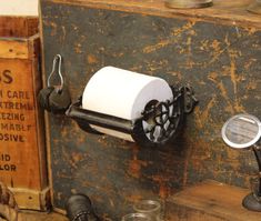 an old fashioned toilet paper dispenser on a wooden shelf next to other items