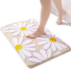 a woman is standing on a mat with white and yellow daisies attached to it