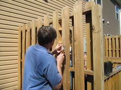 a man standing in front of a wooden fence