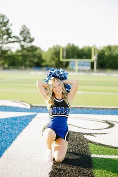 a cheerleader kneeling down on the ground with her hands behind her head and arms in the air