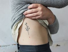 a woman's stomach with a small flower tattoo on it