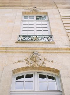 an old building with two windows and a wrought iron balcony