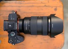 a camera with a lens attached to it's body sitting on a wooden table