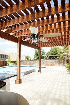 an outdoor patio with a ceiling fan and pool in the backgroung area