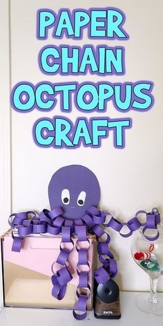 a purple octopus sitting on top of a table next to a box with paper chains attached to it