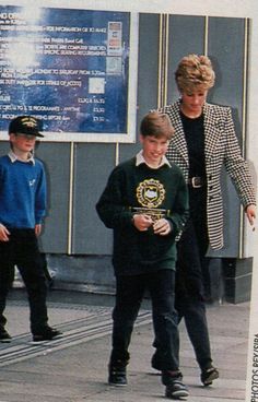 a woman and two boys are walking down the street while looking at their cell phones