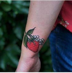 a woman's arm with a strawberry and flowers tattoo on the left side of her wrist