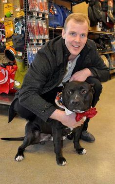 a man holding a dog in his arms while sitting on the floor at a store