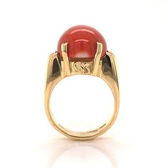 This beautiful Mid-Century cocktail ring features a cabochon cut red coral in 18 karat yellow gold. The coral has a medium scarlet red hue and is set in four golden prongs. The shoulders of the tapered band feature streamlined, openwork spaces for a bit of skin to peek through. From the profile, the Mid-Century details of the ring can truly be admired. The ring has a strong architecture and distinct style, finished in high polish 18k yellow gold. Timeless Cabochon Rings For Formal Occasions, Classic Formal Cabochon Moonstone Ring, Formal Cabochon Ruby Ring, Red Oval Cabochon Signet Ring For Formal Occasions, Classic Carnelian Signet Ring For Formal Events, Classic Carnelian Signet Ring For Formal Occasions, Formal Cabochon Domed Ruby Ring, Formal Red Carnelian Signet Ring, Red Domed Gemstone Rings