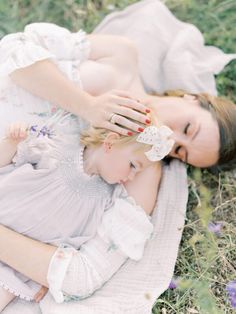 two women laying in the grass with their hands on each other