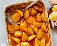 baked potatoes in a baking dish with lemons on the side