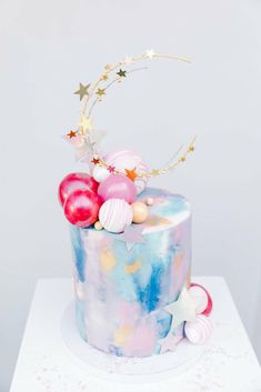 a multi - colored cake with stars and balloons on the top is decorated in pastel colors