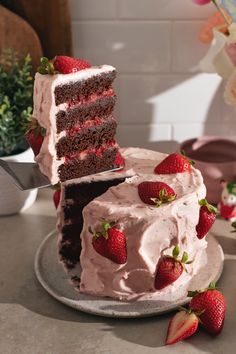 there is a cake with strawberries on the plate and one slice has been cut