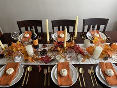 the table is set for thanksgiving dinner with pumpkins, candles and other autumn decorations