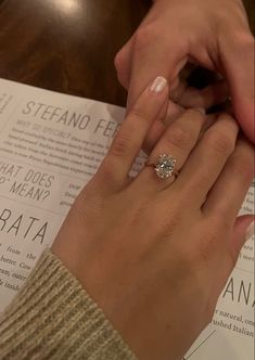 a close up of a person's hand with a ring on top of a paper