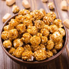 a bowl filled with caramel popcorn on top of a wooden table next to cubes