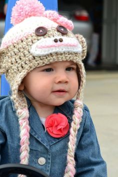 a small child wearing a crocheted hat with a monkey on it's face