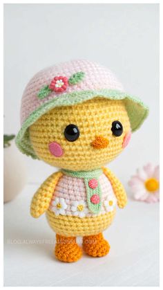 a crocheted doll wearing a pink hat and dress with flowers on the side