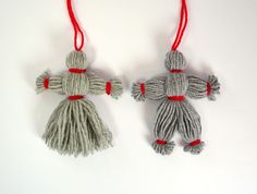 two gray and red ornaments hanging from strings on a white surface, one is made out of yarn