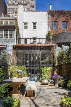 an outdoor patio with tables and potted plants in front of some buildings on a sunny day