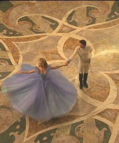 a man and woman are dancing on the floor in blue dresses, with one person wearing a tuxedo