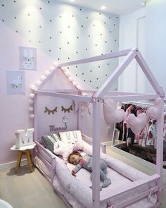 a child's bed with a pink canopy over it and pillows on the floor