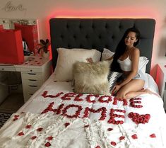 a woman sitting on top of a bed next to a pillow with the word love spelled in it