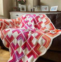 a crocheted blanket sitting on top of a couch next to a brown leather chair