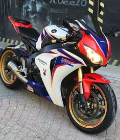 a red, white and blue motorcycle parked in front of a building