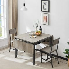 a dining room table with two chairs and a bowl of fruit on the plate next to it