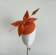 A truly elegant statement orange felt bow cocktail hat with gold detailing. The perfect choice for a winter wedding or special occasion. Made in a stunning shade of burnt orange wool felt, this circular percher style cocktail hat features a double bow in matching orange felt that sits neatly to one side. Wrapped within the bows is a gold arrow head quill which gives this headpiece a statement striking look. Measuring 16cm, it is fitted with a fine elastic in a colour that would blend in with you Elegant Orange Fascinator For Royal Ascot, Elegant Orange Fascinator For Formal Events, Elegant Orange Fascinator For Formal Occasions, Elegant Orange Evening Fascinator, Elegant Orange Headpiece For Evening, Elegant Orange Formal Hat, Orange Mini Hats For Kentucky Derby Evening, Fascinator Ideas, Felt Fascinator