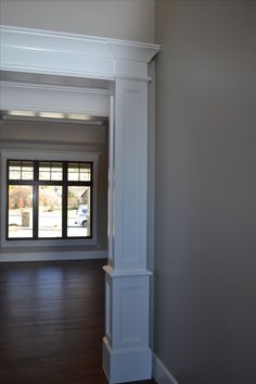 an empty room with wood floors and white columns