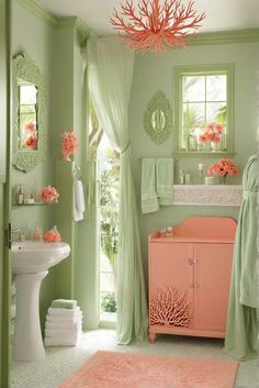 a bathroom with green walls, pink accents and coral accessories on the sink countertop