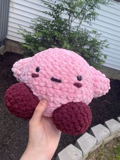 a hand holding a pink crocheted stuffed animal