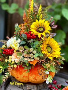 an arrangement of sunflowers and other flowers in a pumpkin