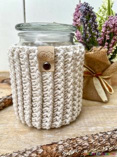 a jar with a button on it sitting next to some flowers