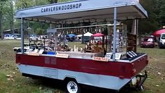 an old fashioned food cart is parked on the grass in front of some trees and other vehicles