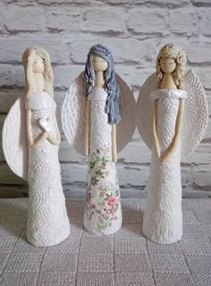 three ceramic angel figurines standing next to each other