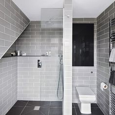 a white toilet sitting in a bathroom next to a walk in shower and tiled walls