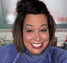 a woman smiling and wearing a blue sweater