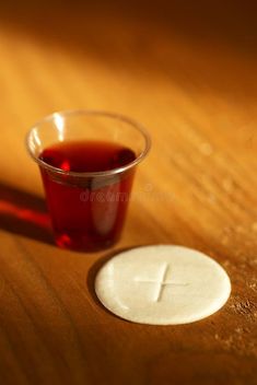 a cup of tea next to a small white cross on a wooden table stock photos