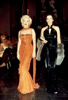 two women in evening dresses standing next to each other