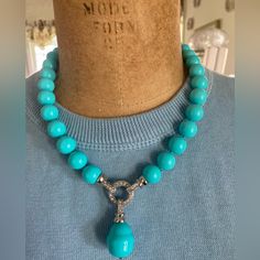 a blue necklace with a silver cross on it and turquoise beads hanging from the neck