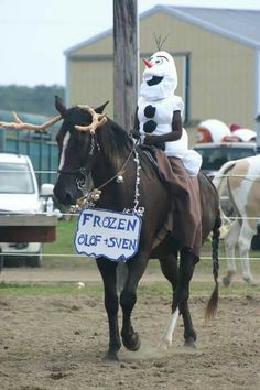 a man riding on the back of a brown horse next to a white snowman