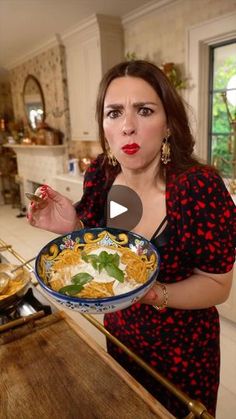 a woman holding a bowl of food in her hand and looking at the camera with an angry look on her face