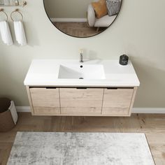 a bathroom vanity with a round mirror above it and a white rug on the floor