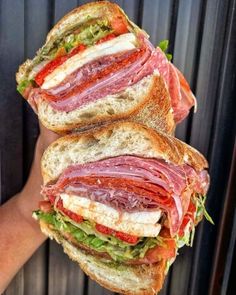 two sandwiches stacked on top of each other in front of a person's hand