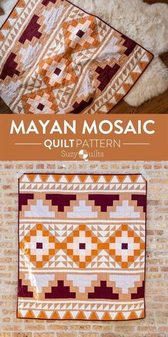 an orange and white quilt sitting on top of a wooden floor next to a brick wall